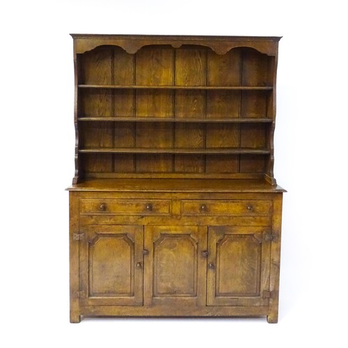 1729 - A 20thC oak dresser with a shaped three tier plate rack, the base comprising two short drawers over ... 