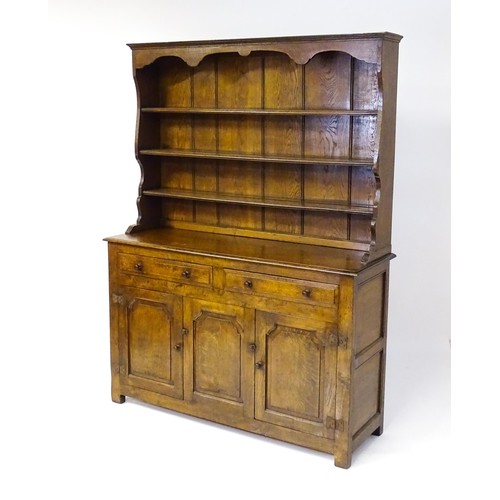 1729 - A 20thC oak dresser with a shaped three tier plate rack, the base comprising two short drawers over ... 