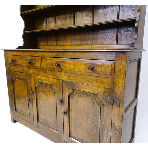 1729 - A 20thC oak dresser with a shaped three tier plate rack, the base comprising two short drawers over ... 