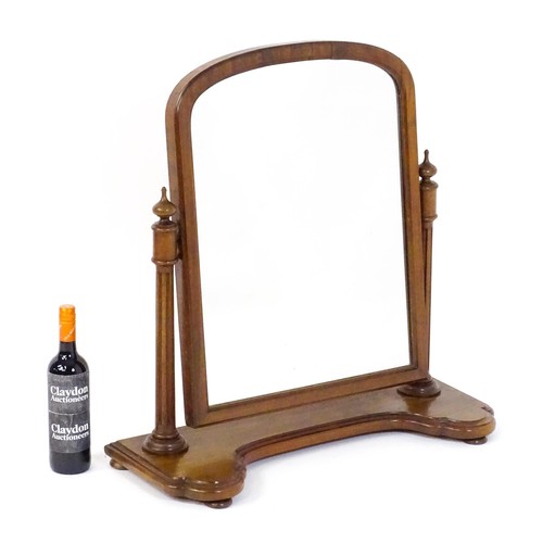 1734 - A 19thC mahogany toilet mirror with an arched frame, fluted supports with turned finial terminals an... 