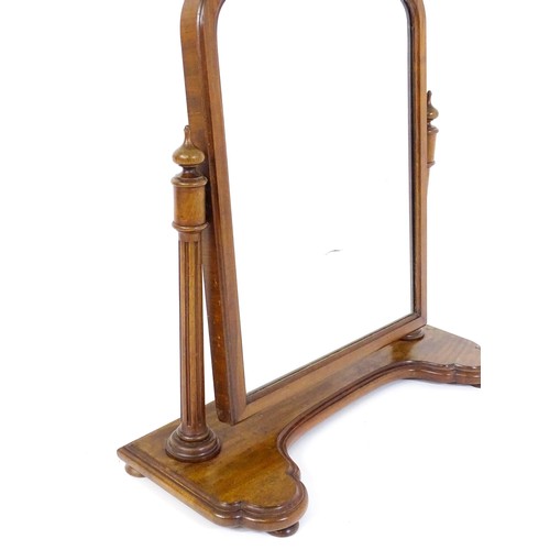 1734 - A 19thC mahogany toilet mirror with an arched frame, fluted supports with turned finial terminals an... 