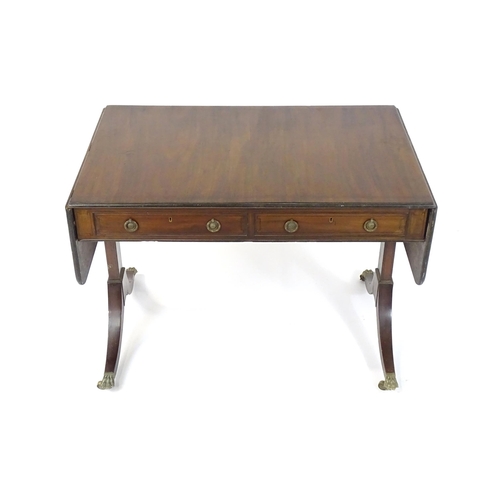 1745 - A Regency rosewood sofa table with ebonised stringing to the top and drop flaps to either side, the ... 