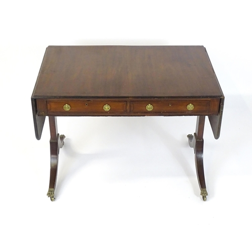 1745 - A Regency rosewood sofa table with ebonised stringing to the top and drop flaps to either side, the ... 