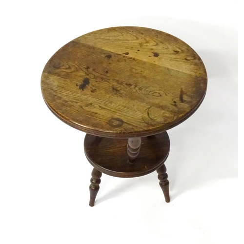 1764 - An early 20thC oak cricket table with a circular table top above three turned supports connected to ... 