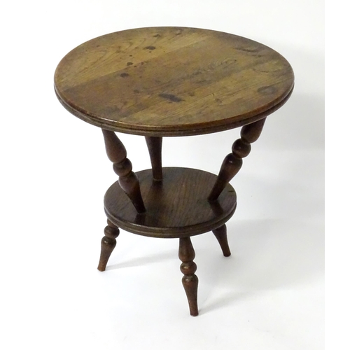 1764 - An early 20thC oak cricket table with a circular table top above three turned supports connected to ... 