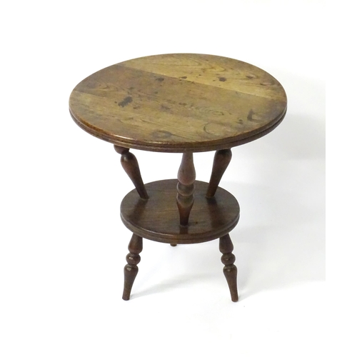 1764 - An early 20thC oak cricket table with a circular table top above three turned supports connected to ... 