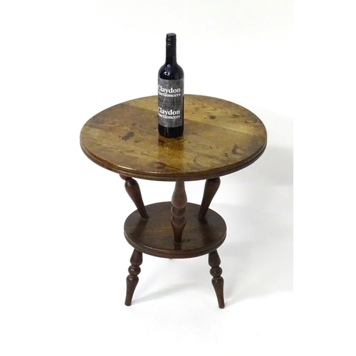 1764 - An early 20thC oak cricket table with a circular table top above three turned supports connected to ... 