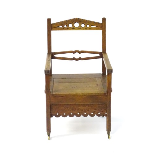 1765 - An Arts and Crafts style oak chair, having a pierced pointed top rail and shaped mid rail above a hi... 