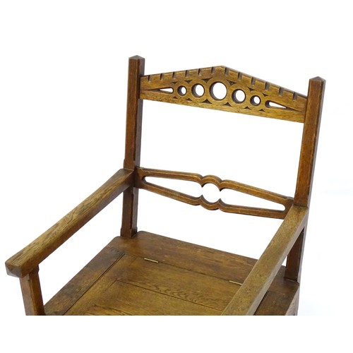 1765 - An Arts and Crafts style oak chair, having a pierced pointed top rail and shaped mid rail above a hi... 