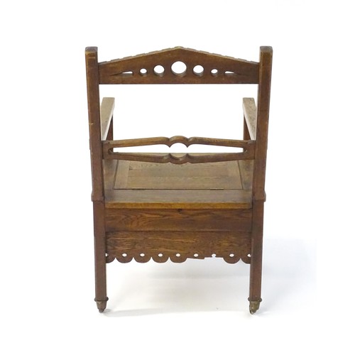 1765 - An Arts and Crafts style oak chair, having a pierced pointed top rail and shaped mid rail above a hi... 