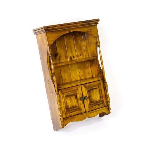 1778 - A small wall hanging cabinet of pine construction, with a moulded cornice above two shelves and two ... 