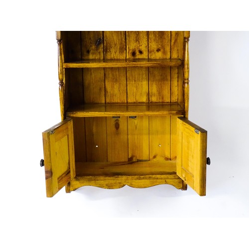 1778 - A small wall hanging cabinet of pine construction, with a moulded cornice above two shelves and two ... 