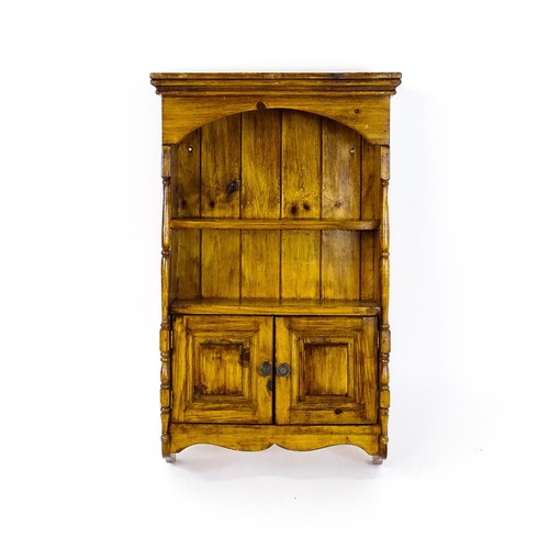 1778 - A small wall hanging cabinet of pine construction, with a moulded cornice above two shelves and two ... 