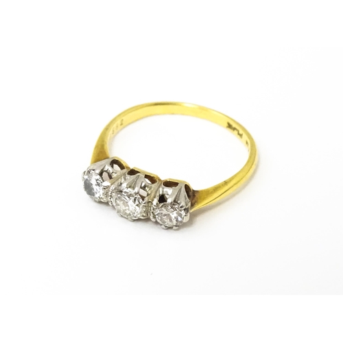 615 - An 18ct gold ring with a platinum set trio of diamonds. Ring size approx. N