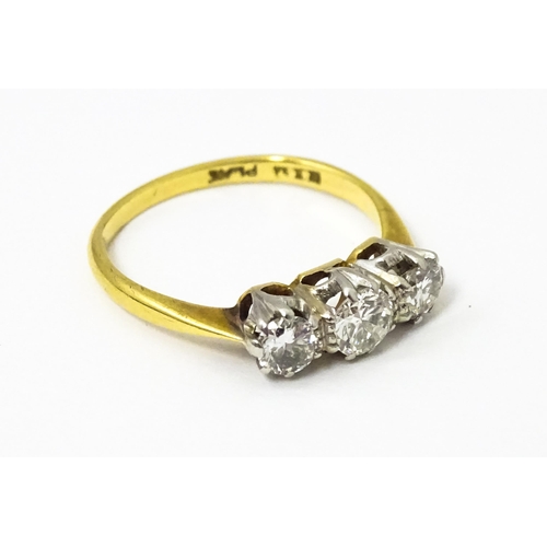 615 - An 18ct gold ring with a platinum set trio of diamonds. Ring size approx. N