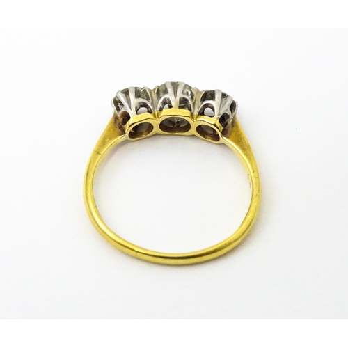 615 - An 18ct gold ring with a platinum set trio of diamonds. Ring size approx. N