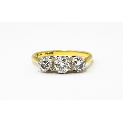 615 - An 18ct gold ring with a platinum set trio of diamonds. Ring size approx. N