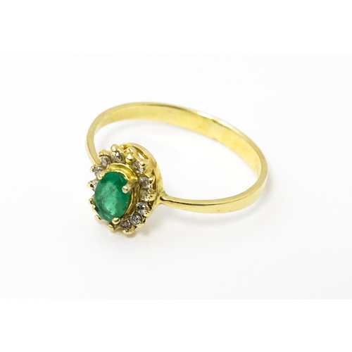 617 - A gold ring set with central emerald bordered by diamonds. Ring size approx R