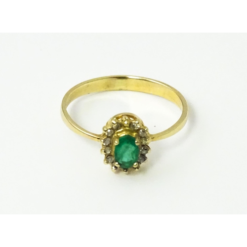 617 - A gold ring set with central emerald bordered by diamonds. Ring size approx R