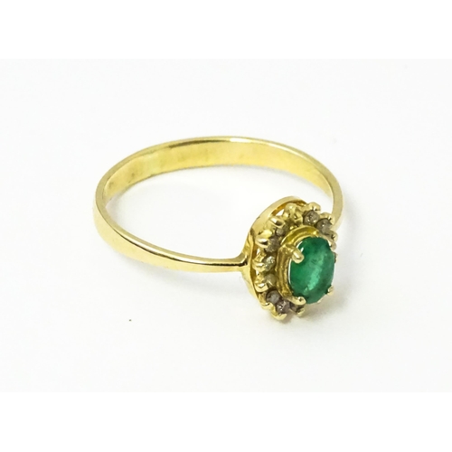 617 - A gold ring set with central emerald bordered by diamonds. Ring size approx R