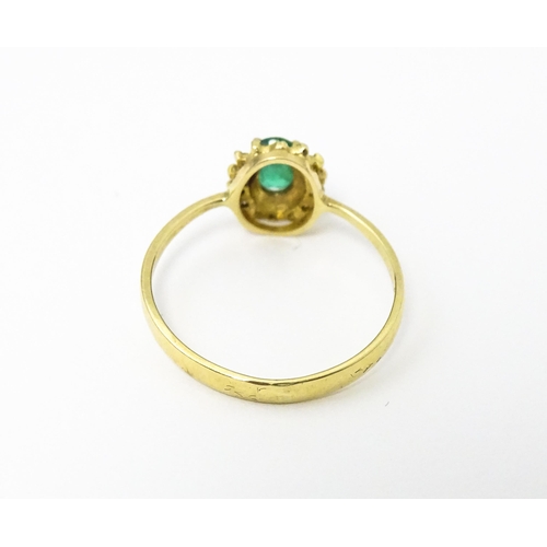 617 - A gold ring set with central emerald bordered by diamonds. Ring size approx R