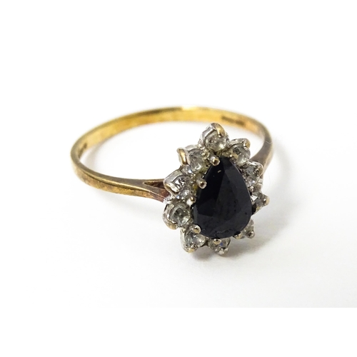 618 - A 9ct gold ring set with central blue stone bordered by white stones. Ring size approx. L 1/2