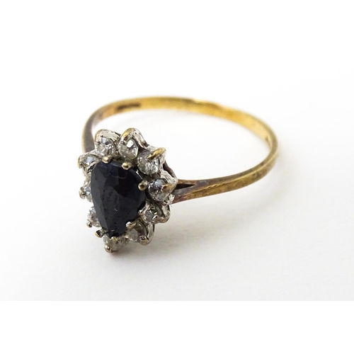 618 - A 9ct gold ring set with central blue stone bordered by white stones. Ring size approx. L 1/2