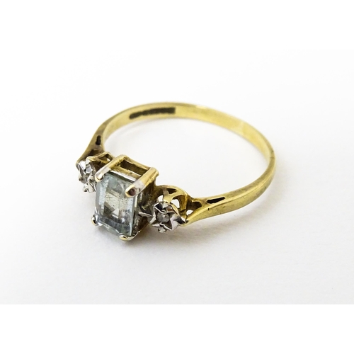 621 - A 9ct gold ring set with central aquamarine flanked by illusion set diamonds. Ring size approx. I 1/... 