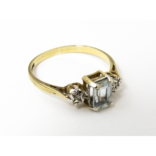 621 - A 9ct gold ring set with central aquamarine flanked by illusion set diamonds. Ring size approx. I 1/... 