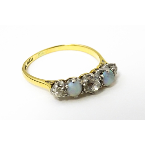 623 - An 18ct ring set with two opals and three diamonds. Ring size approx. O 1/2