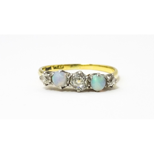 623 - An 18ct ring set with two opals and three diamonds. Ring size approx. O 1/2