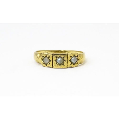 628 - A 9ct gold ring set with three seed pearls. Ring size approx. M