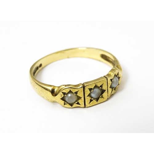 628 - A 9ct gold ring set with three seed pearls. Ring size approx. M