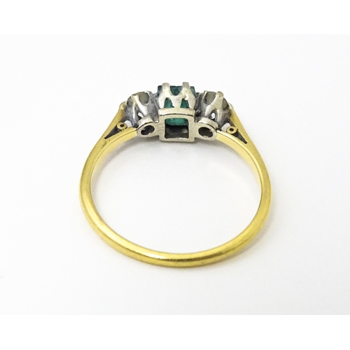 631 - An 18ct gold ring set with central emerald flanked by diamonds. Ring size approx. L