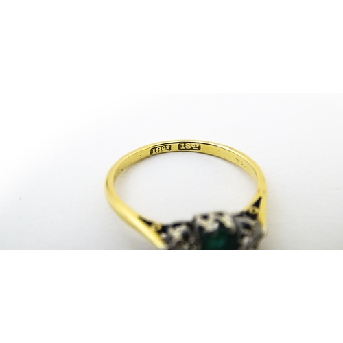 631 - An 18ct gold ring set with central emerald flanked by diamonds. Ring size approx. L