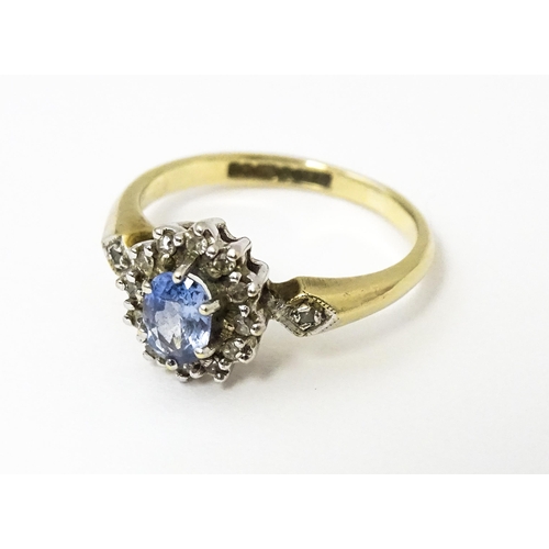 632 - A 9ct gold ring set with central topaz bordered by diamonds flanked by further diamonds to shoulders... 