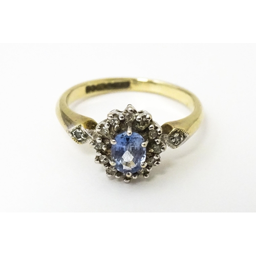 632 - A 9ct gold ring set with central topaz bordered by diamonds flanked by further diamonds to shoulders... 