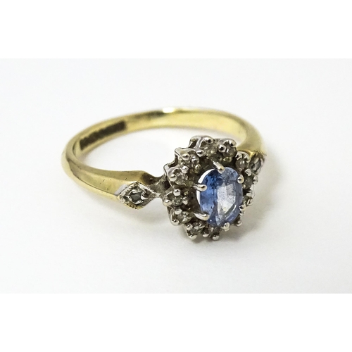 632 - A 9ct gold ring set with central topaz bordered by diamonds flanked by further diamonds to shoulders... 