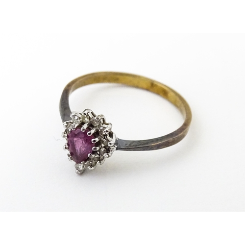 640 - A yellow metal ring set with pink sapphire flanked by diamonds. Ring size approx. M