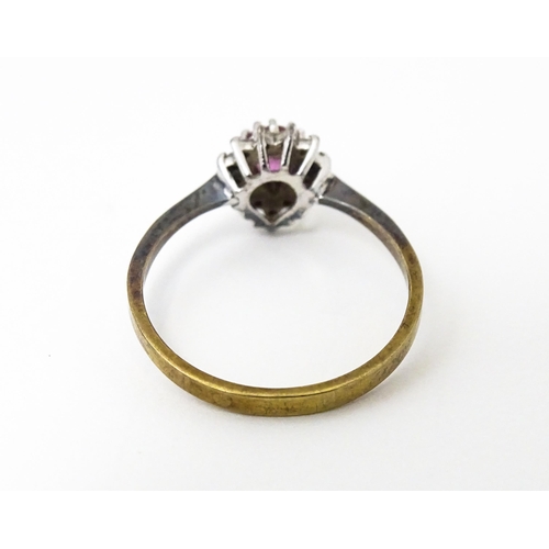 640 - A yellow metal ring set with pink sapphire flanked by diamonds. Ring size approx. M