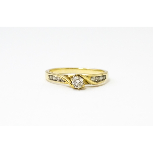 641 - A 9ct gold ring set with central diamond flanked by four further diamonds to each shoulder. Ring siz... 