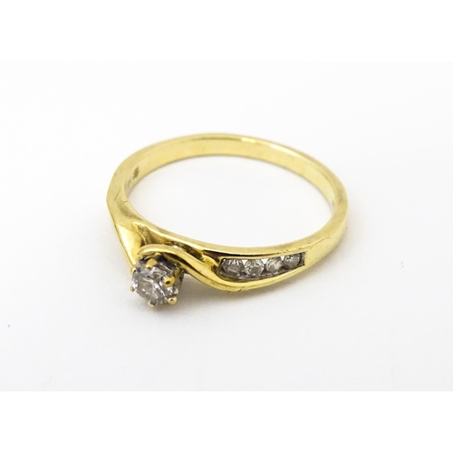 641 - A 9ct gold ring set with central diamond flanked by four further diamonds to each shoulder. Ring siz... 