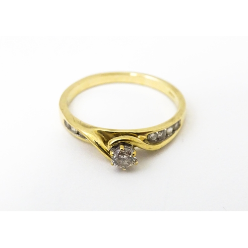 641 - A 9ct gold ring set with central diamond flanked by four further diamonds to each shoulder. Ring siz... 