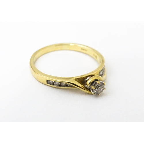 641 - A 9ct gold ring set with central diamond flanked by four further diamonds to each shoulder. Ring siz... 