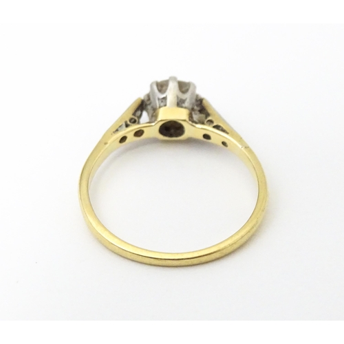 649 - An 18ct gold ring with platinum set central diamond flaked by three further diamonds to each shoulde... 