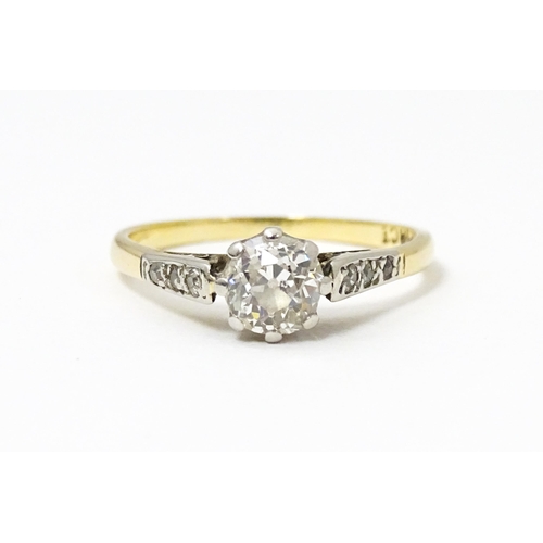 649 - An 18ct gold ring with platinum set central diamond flaked by three further diamonds to each shoulde... 