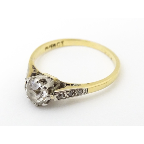 649 - An 18ct gold ring with platinum set central diamond flaked by three further diamonds to each shoulde... 