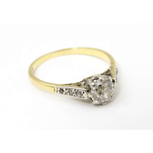 649 - An 18ct gold ring with platinum set central diamond flaked by three further diamonds to each shoulde... 