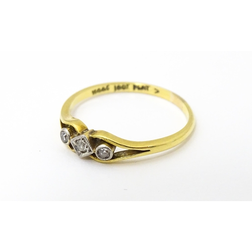 651 - An 18ct gold ring with platinum set central diamond flanked by two further diamonds. Ring size appro... 