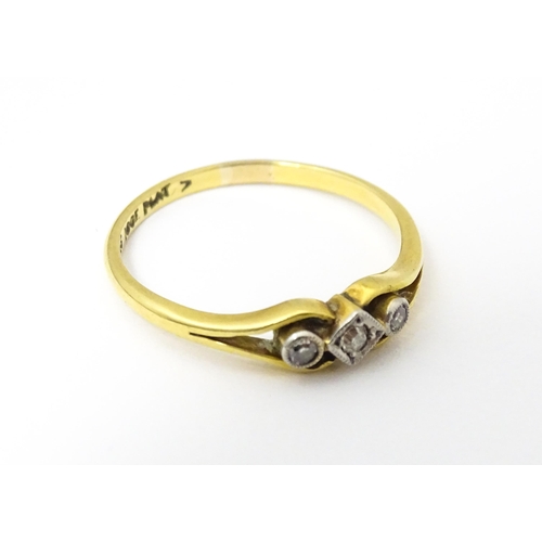 651 - An 18ct gold ring with platinum set central diamond flanked by two further diamonds. Ring size appro... 